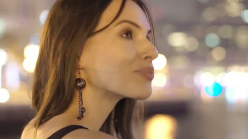 Jovem feliz gosta de luzes da cidade à noite em pé perto do rio
