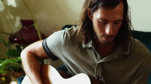 Man Playing Acoustic Guitar in Living Room