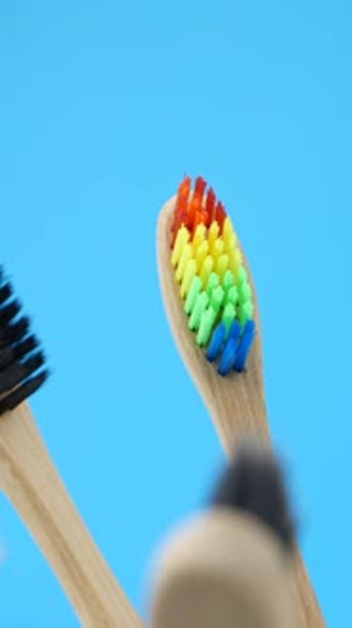 Wooden Toothbrushes with Colorful Bristles on Blue Background