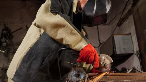 Nahaufnahme eines jungen Handwerkers, der eine Metallschleifmaschine in einer Fabrik benutzt