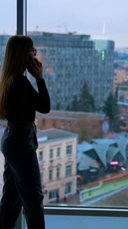 Young Adult Talking on Phone by Office Window