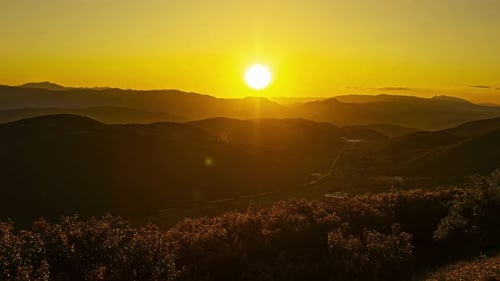 Zeitraffer des Sonnenuntergangs über sanften Hügeln mit fernen Bergen und Flusstälern