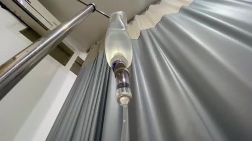 intravenous drip with a hospital curtain in the background - Hospital room