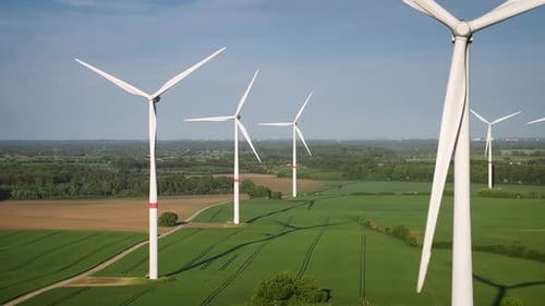 Aerial footage of wind farm with large spinning wind turbines. Aerial flying over renewable energy w