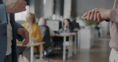 Closeup of Men Colleagues Gesturing During Conversation Then Shaking Hands Making Deal in Office