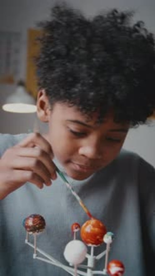 Portrait of Cheerful Little Boy Coloring DIY Solar System with Paint