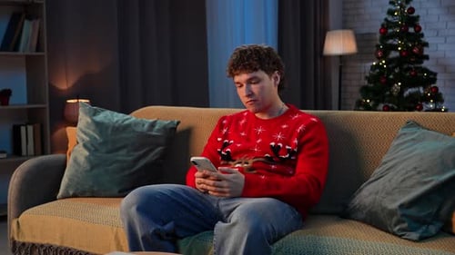 Young Man Using Smartphone at Christmas Indoors