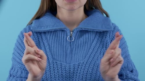 Woman Crossing Fingers on Blue Background
