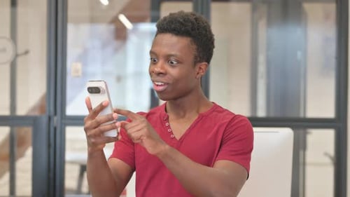Young Adult Smiling While Using Phone in Office