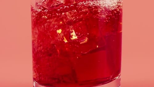Red Soda Being Poured Over Ice Cubes