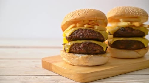 Two Double Cheeseburgers Topped with Fries on Cutting Board
