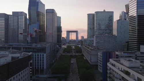 Forwards Fly Above Wide Pedestrian Boulevard in Super Modern Business District La Defense at Sunset