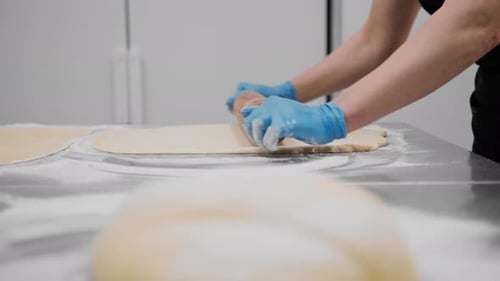 The kitchen in the bakery - the process of preparing cinnabons, the woman baker forms doughs