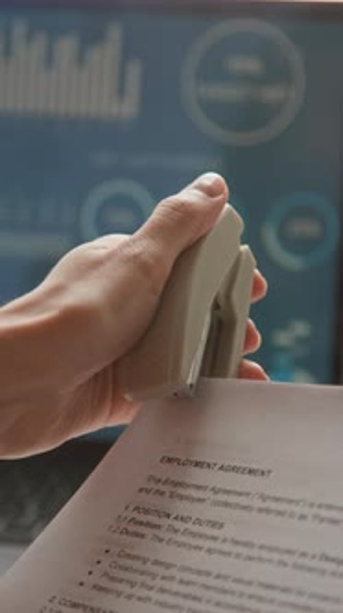 Office Worker Stapling Documents at Desk