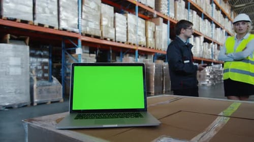 Laptop with Green Screen in Logistics Warehouse. Great for Mock-up usage.