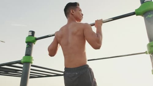 Young athletic man does pulls up on the crossbar