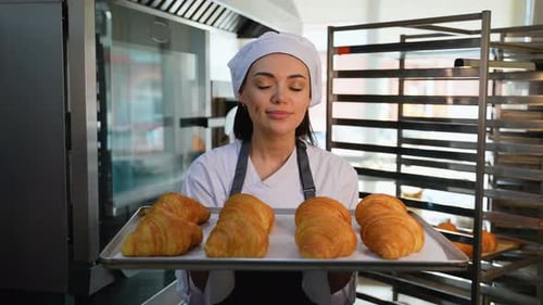 Smiling Baker Woman Holding Fresh Croissants