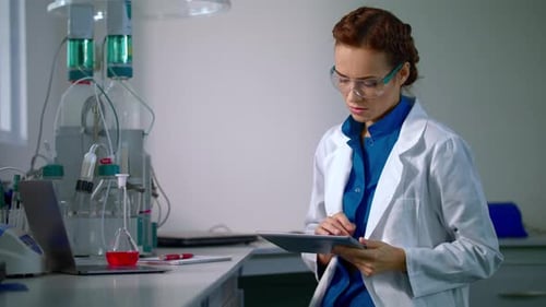 Female scientist works with tablet in modern science laboratory research