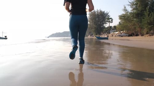 Young Sporty Woman Jogging Along Sandy Beach