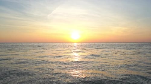 Un coucher de soleil rose et orange se forme sous un soleil couchant éclatant.