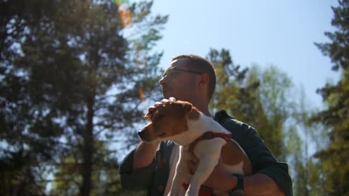 Man Holds Cute Dog in Sunny Forest