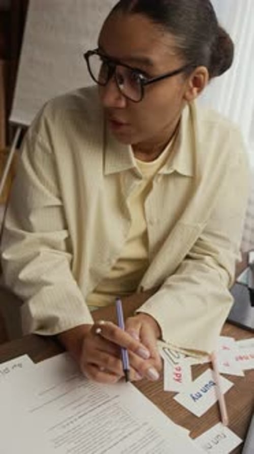 Tutor Helping Student with Task at Desk in Room