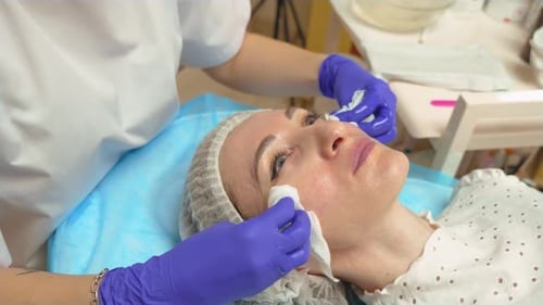 Cosmetologist Doctor Cleaning Woman Face with Cotton Wipes Pads at Spa Salon