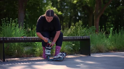 young hipster girl puts on roller skates in skate park before starting skating street extreme sport