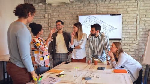 Group of young business people discussing architectural designs in office.