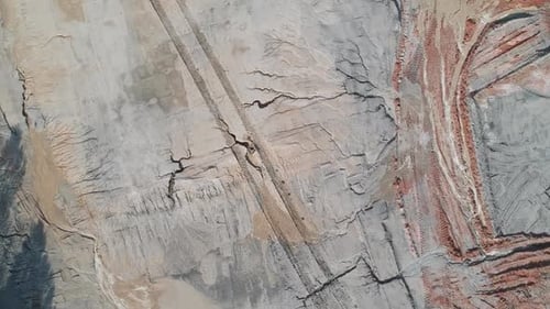 Birds eye view looking straight down at otherworldly terrain with tire tracks in dirt, outside on a