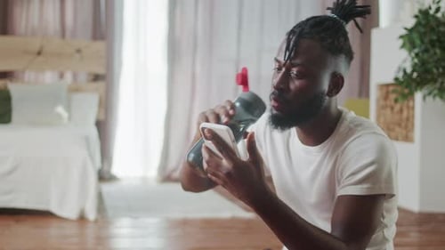 Young Adult Using Phone, Drinking Water Indoors