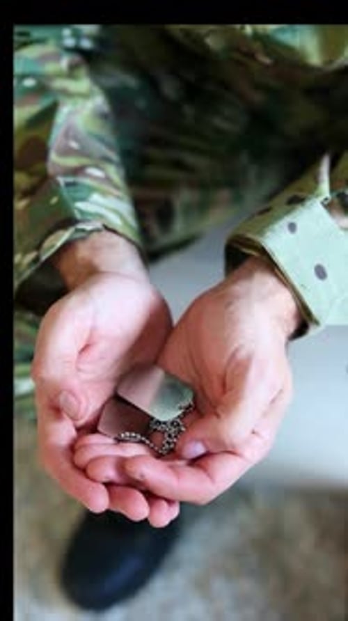 vertical Soldier holding dog tags suffering from post-traumatic stress disorder