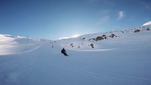 unerkennbarer Skifahrer, der an einem blauen, sonnigen Tag in Zeitlupe einen Sprung macht