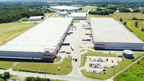 Aerial Shot of Truck with Attached Semi Trailer Leaving Industrial Warehouse/ Storage Building/ Load