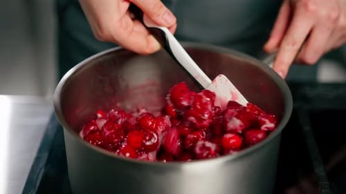 Closeup in Professional Kitchen Mixing Cherries with a Spatula in a Saucepan for Jam