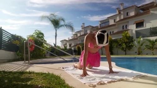 A Woman Practices Yoga Outdoors By the Pool Using a VR Headset for a Modern Workout