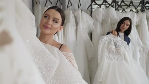 Duas noivas felizes escolhem seu vestido de noiva no salão de casamento