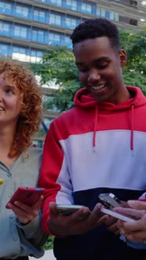 Friends Sharing Content on Mobile Phones in City