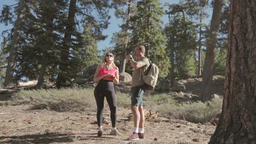 Male Hiker in Green Shorts Drinking Water During Hiking Stop in the Forest with His Girl Friend