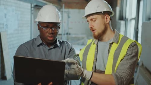 Black Engineer Discussing Project on Laptop to Construction Site Worker
