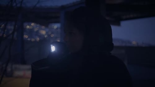 A Mysterious Person with a Flashlight in a Dark City at Night Evoking Intrigue and Solitude