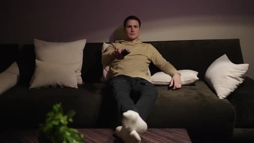 Man Relaxes on Couch at Home at Night