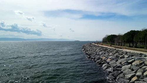 Summer scene of rocky coastal area near park by the sea, drone fly forward shot