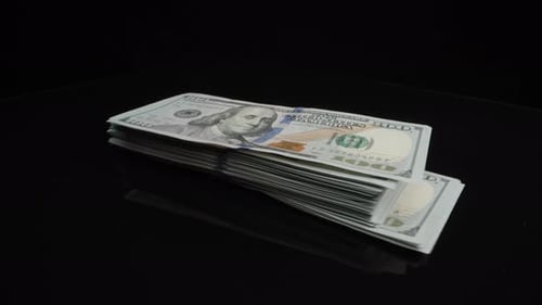 Stack of Money Rotating on Reflective Surface