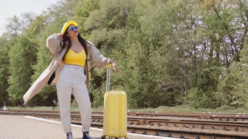 Stylish Woman with Suitcase Waiting at Train Station