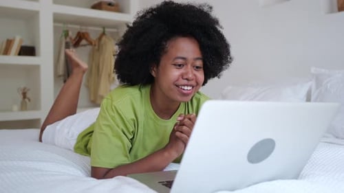 Young Woman Relaxing, Using Laptop on Bed
