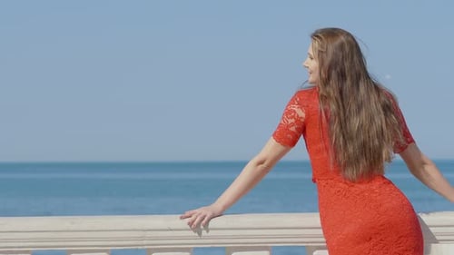 young woman looking out from a terrace overlooking the sea enjoying the view