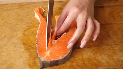 Slicing Fresh Salmon Steak on Cutting Board