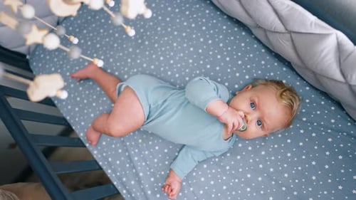 Baby Lying Awake in Crib Looking at Mobile
