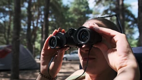 Woman Using Binoculars While Camping in Forest